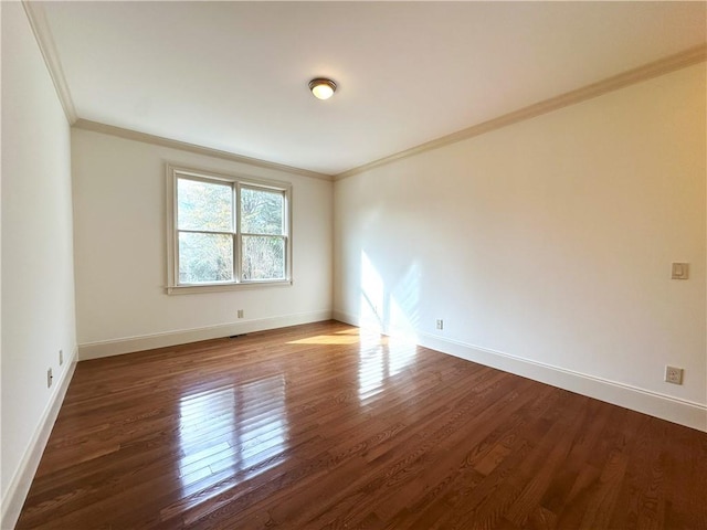 empty room with baseboards, wood finished floors, and ornamental molding