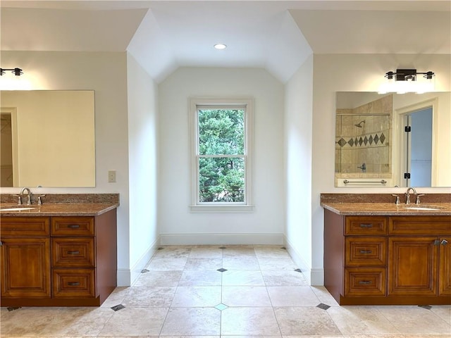 full bath with a sink, tiled shower, two vanities, and vaulted ceiling