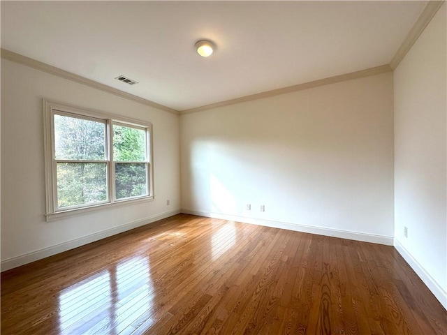 unfurnished room featuring visible vents, wood-type flooring, baseboards, and crown molding