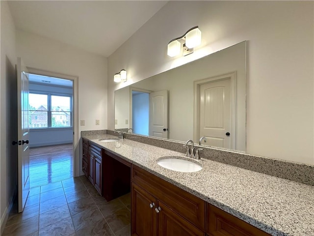 bathroom featuring a sink, baseboards, and double vanity