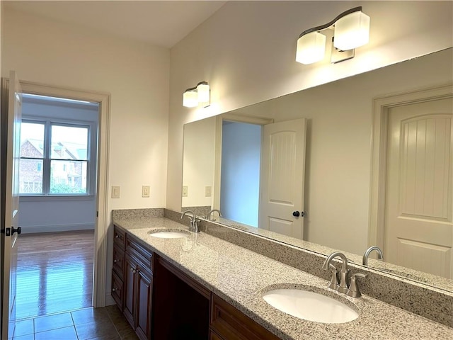 bathroom with tile patterned flooring, double vanity, baseboards, and a sink