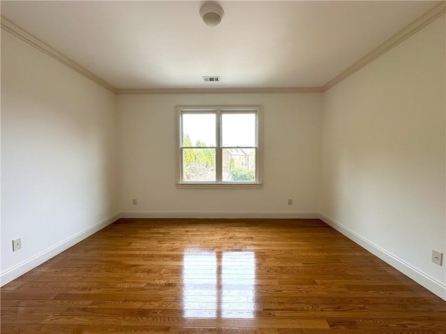 unfurnished room featuring visible vents, baseboards, wood finished floors, and crown molding