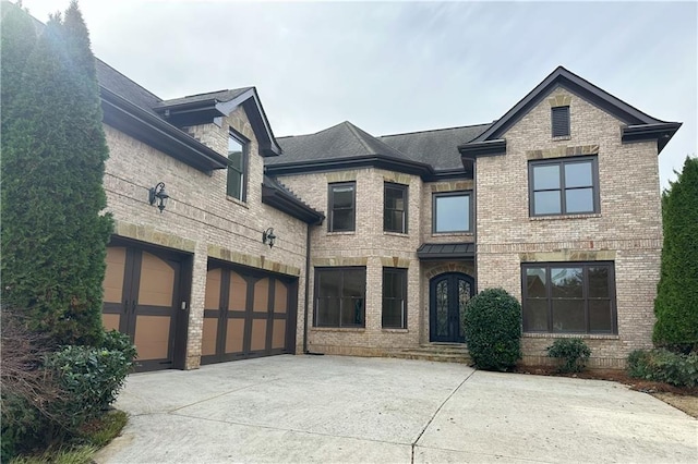 view of front of property with brick siding, concrete driveway, roof with shingles, french doors, and a garage