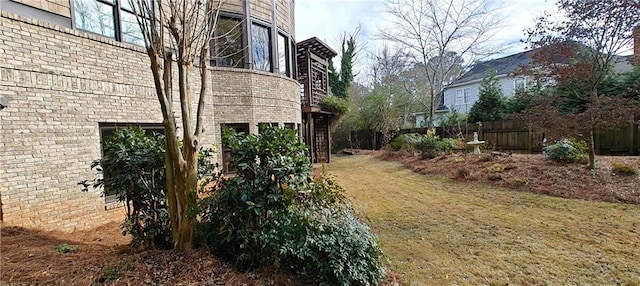 view of home's exterior featuring a lawn, brick siding, and fence