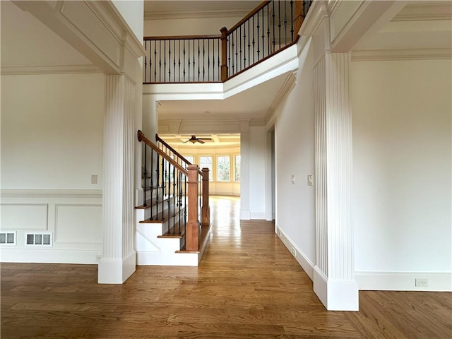 interior space featuring visible vents, stairway, ornamental molding, wood finished floors, and a decorative wall