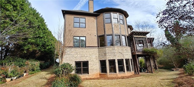 rear view of property featuring a yard, brick siding, and a chimney