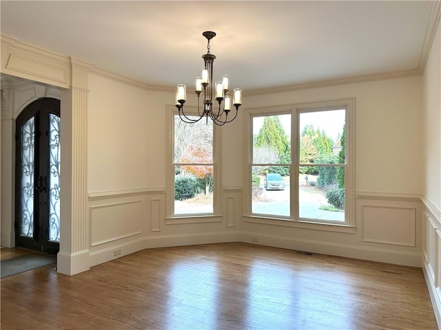 unfurnished dining area with a notable chandelier, arched walkways, light wood-style floors, and crown molding