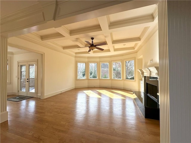 unfurnished living room with plenty of natural light, wood finished floors, a fireplace, and ornamental molding