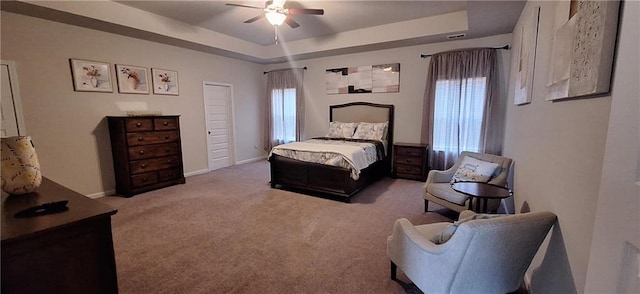 bedroom featuring light colored carpet, a raised ceiling, and ceiling fan