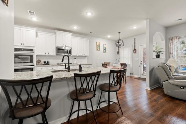 kitchen featuring white cabinetry, sink, a kitchen breakfast bar, stainless steel appliances, and dark wood-type flooring