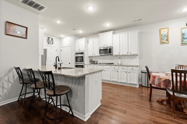 kitchen featuring dark wood-type flooring, a breakfast bar, sink, stainless steel appliances, and white cabinets