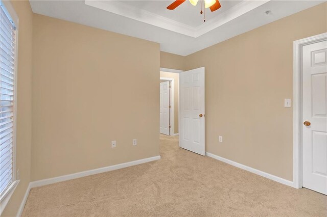 carpeted empty room with ceiling fan, a raised ceiling, and plenty of natural light