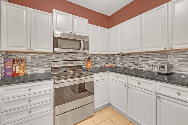 kitchen featuring decorative backsplash, stainless steel appliances, white cabinets, and light tile patterned floors