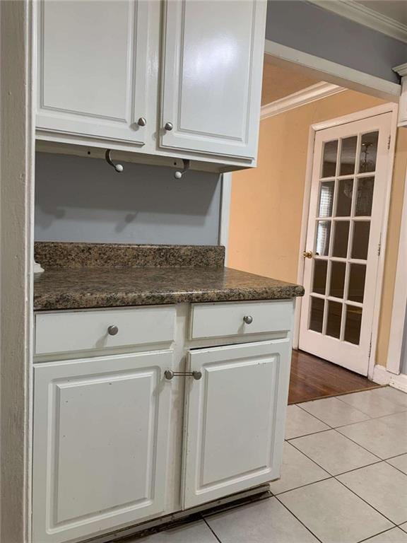 kitchen featuring crown molding, white cabinetry, and light tile patterned floors