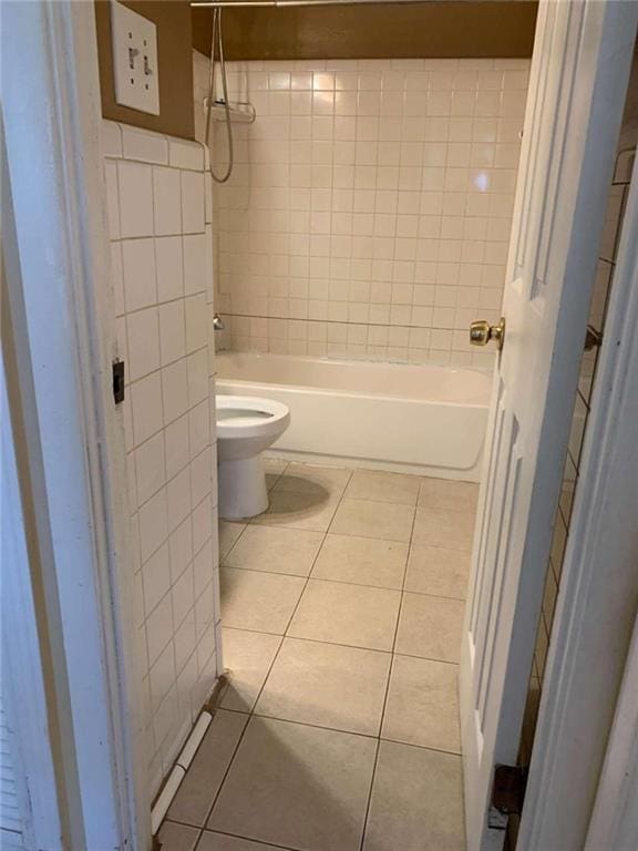 bathroom featuring toilet, tiled shower / bath combo, and tile patterned floors