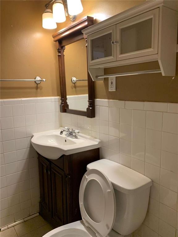 bathroom featuring tile walls, vanity, toilet, and tile patterned floors