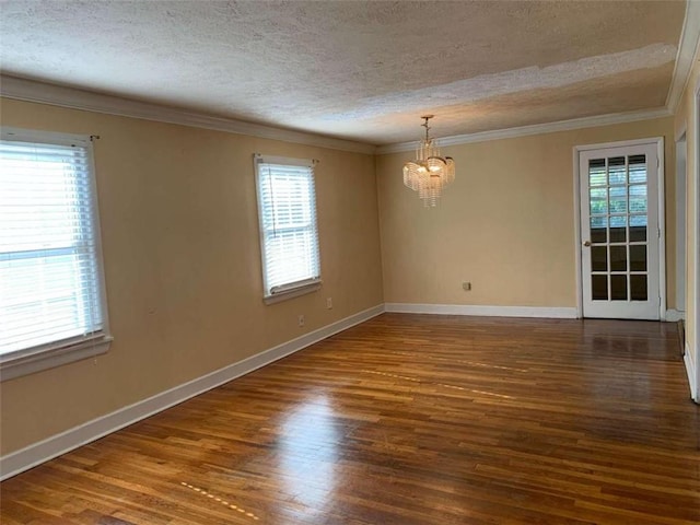 spare room featuring ornamental molding, a textured ceiling, a healthy amount of sunlight, and dark hardwood / wood-style flooring