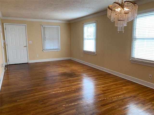 unfurnished room with crown molding, a chandelier, and dark hardwood / wood-style flooring