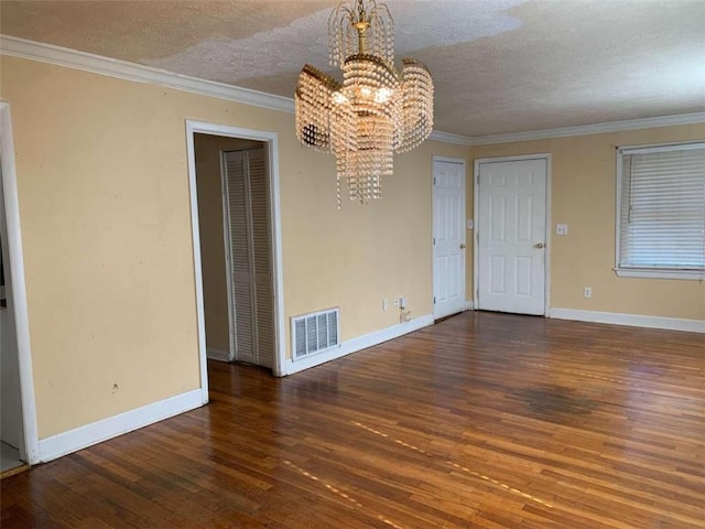 unfurnished room featuring a textured ceiling, ornamental molding, dark hardwood / wood-style flooring, and a chandelier