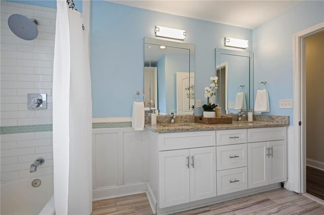 full bathroom featuring double vanity, wood finished floors, a sink, and shower / tub combination