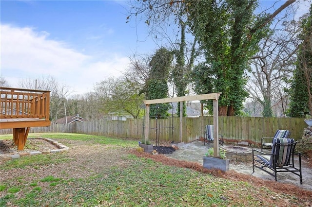 view of yard featuring a fenced backyard, a fire pit, and a wooden deck