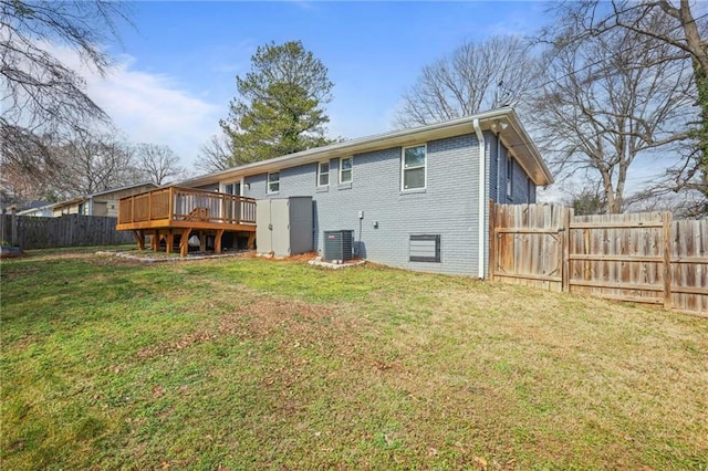 rear view of property with a fenced backyard, central AC unit, a lawn, and brick siding