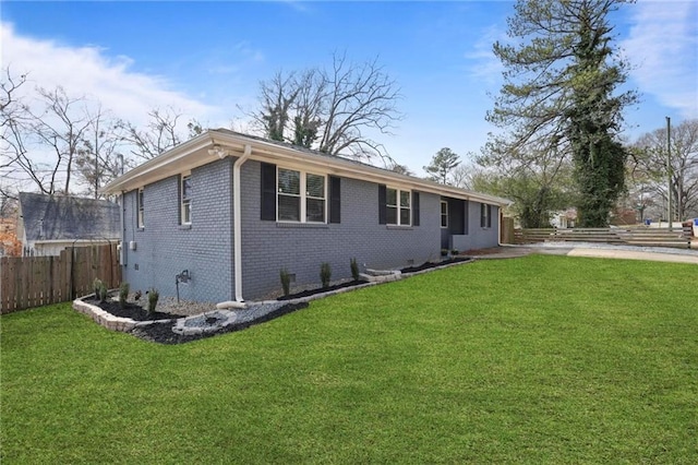 ranch-style house featuring a front yard, brick siding, and fence