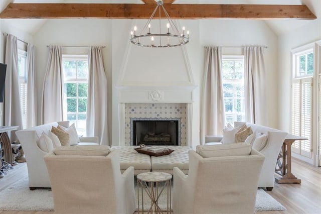 living room with a chandelier, a wealth of natural light, light hardwood / wood-style floors, and a tiled fireplace