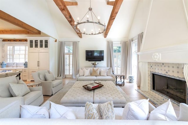 living room featuring a fireplace, light hardwood / wood-style floors, beam ceiling, and a healthy amount of sunlight