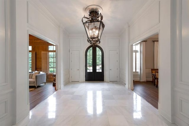 entryway with a chandelier, french doors, and ornamental molding