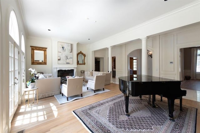 sitting room with decorative columns, light hardwood / wood-style flooring, and ornamental molding