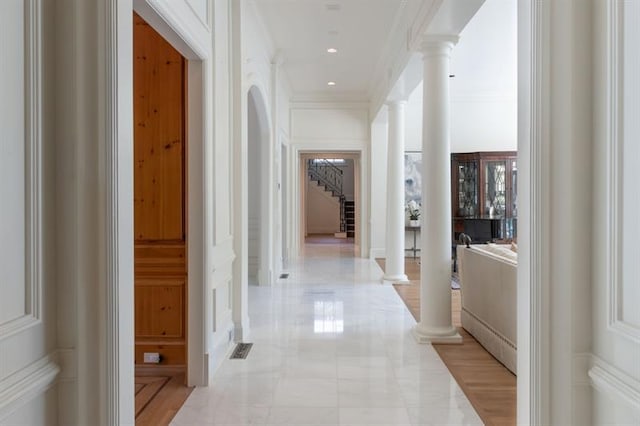 hall featuring decorative columns and ornamental molding