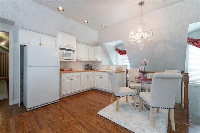 kitchen featuring decorative light fixtures, white appliances, white cabinetry, and dark hardwood / wood-style flooring