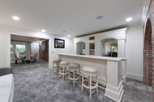 bar featuring ornamental molding, white cabinetry, and dark colored carpet