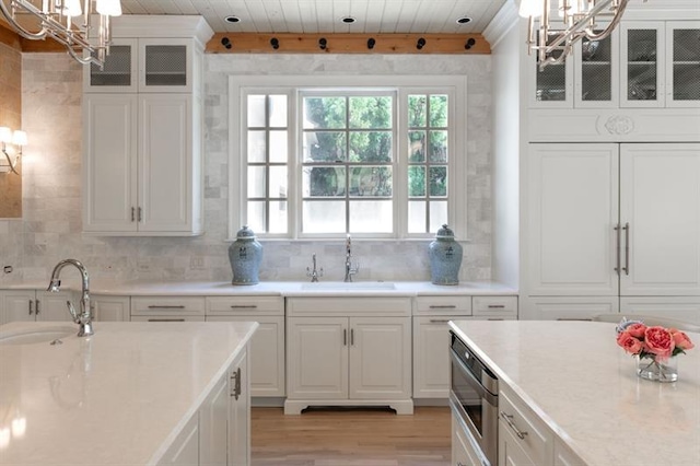 kitchen with pendant lighting, sink, white cabinetry, and decorative backsplash