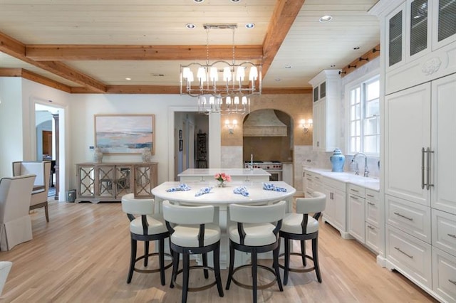 dining space featuring sink, beam ceiling, wood ceiling, and light hardwood / wood-style flooring