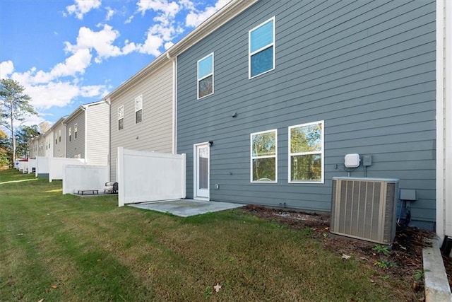 back of property with a lawn, cooling unit, and a patio area