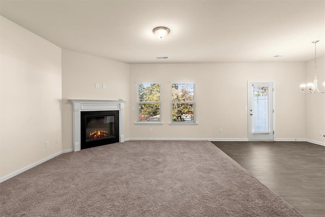 unfurnished living room featuring dark carpet and a notable chandelier