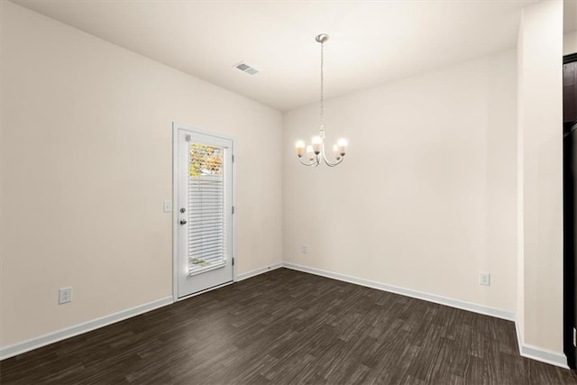 spare room featuring dark hardwood / wood-style flooring and an inviting chandelier