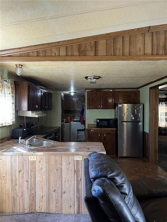 kitchen with a healthy amount of sunlight, stainless steel fridge, washing machine and dryer, and a textured ceiling