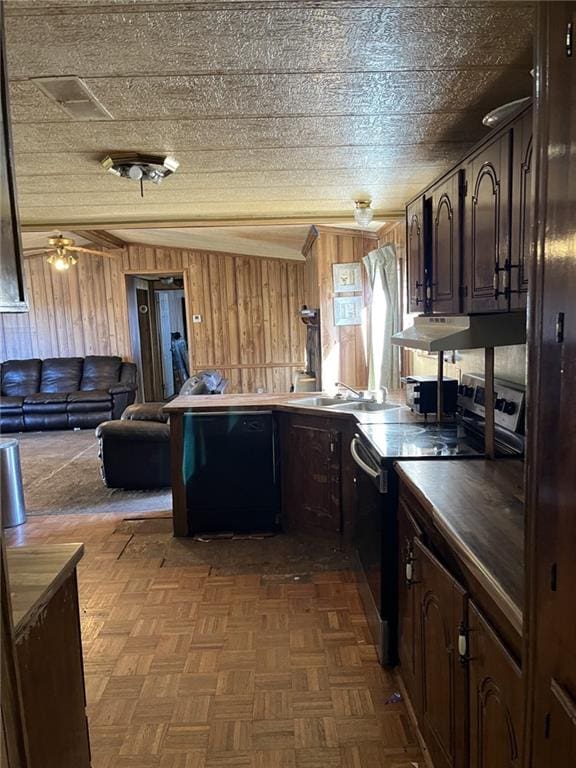 kitchen with dark brown cabinetry, parquet flooring, black appliances, and wood walls