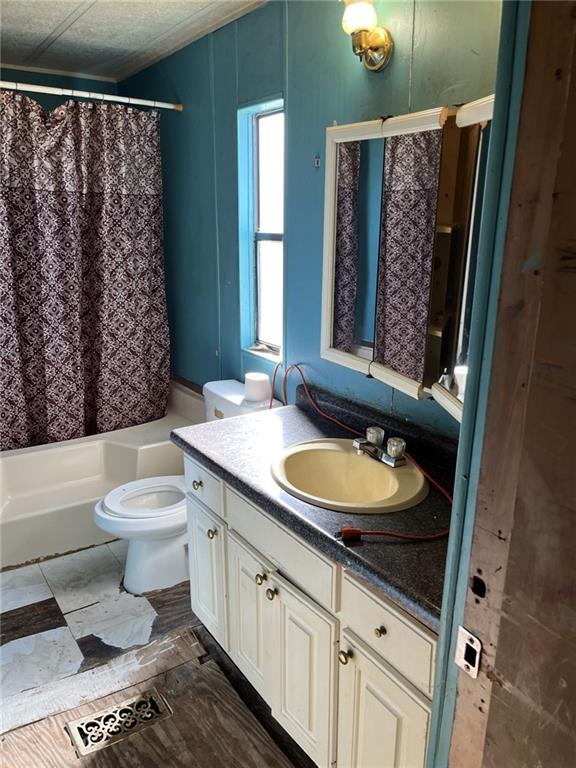 full bathroom featuring vanity, shower / bath combination with curtain, a textured ceiling, and toilet