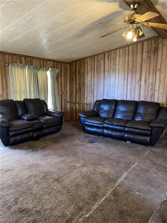 living room with ceiling fan, carpet, and wooden walls