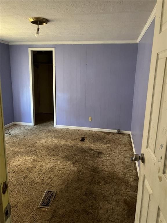 empty room with ornamental molding, carpet flooring, and a textured ceiling