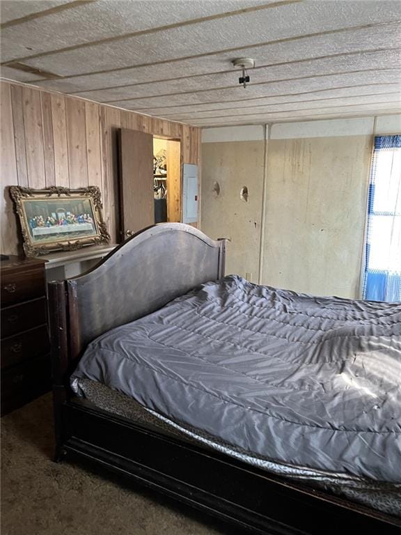 bedroom with electric panel, carpet, and wood walls