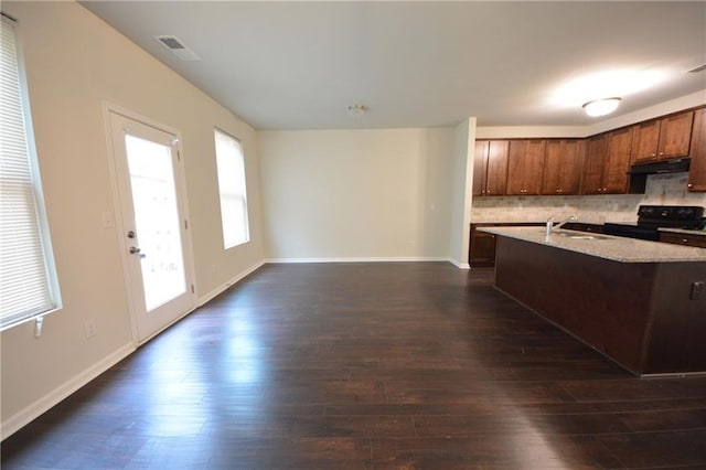 kitchen featuring dark wood-type flooring, a kitchen island with sink, a wealth of natural light, and black electric range