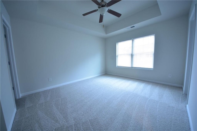 carpeted spare room featuring ceiling fan and a tray ceiling