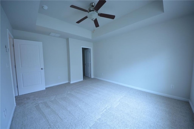 unfurnished bedroom featuring carpet, ceiling fan, and a raised ceiling