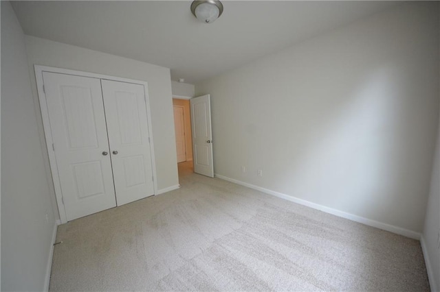 unfurnished bedroom with light carpet and a closet