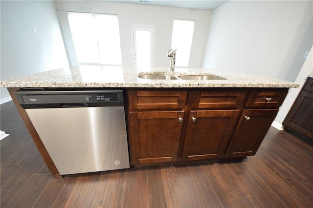 kitchen with light stone countertops, dishwasher, dark wood-type flooring, sink, and a kitchen island with sink